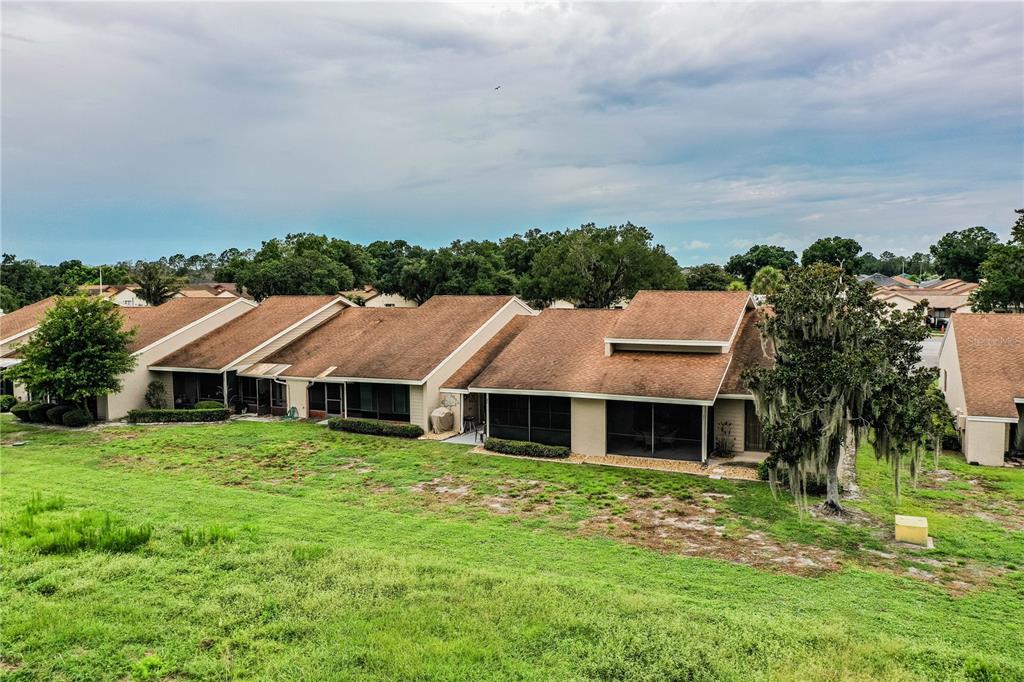 An exterior view of a row of attached townhouses with brown roofs and screened lanais — 5225 IMPERIAL LAKES BOULEVARD UNIT 22, MULBERRY, FL