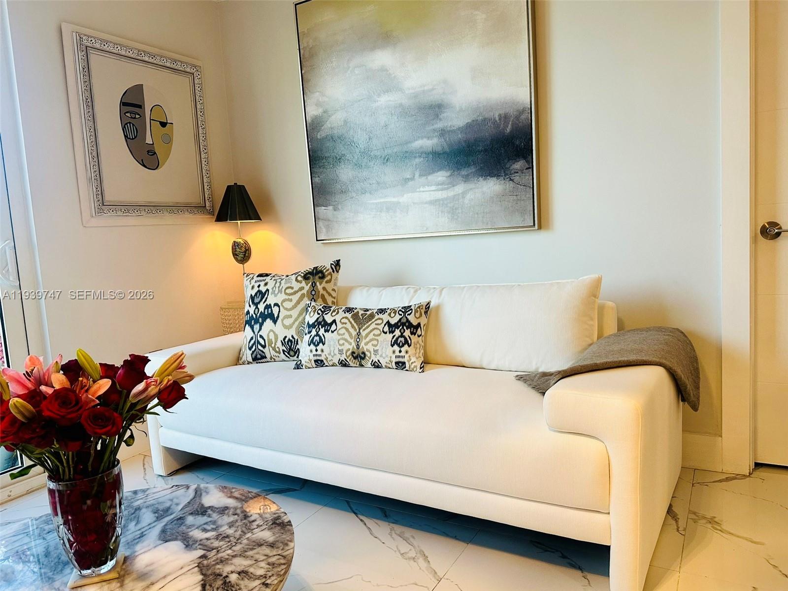 A white sofa sits in a living room with a marble table and abstract art — 1740 NW N River Dr # 626, Miami FL 33125, MIAMI, FL