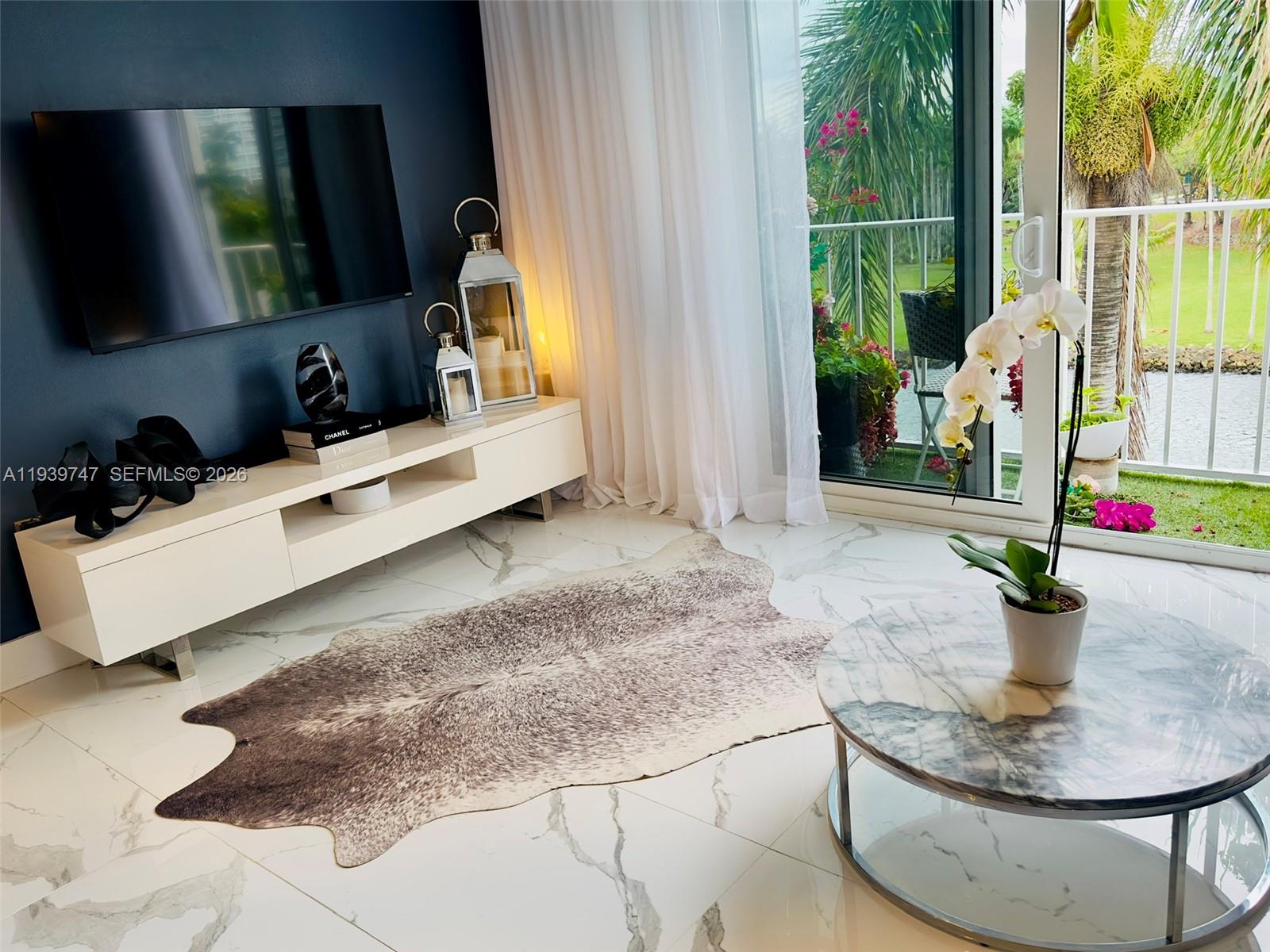 A living room features a dark accent wall, white media console, marble floors, and balcony view — 1740 NW N River Dr # 626, Miami FL 33125, MIAMI, FL