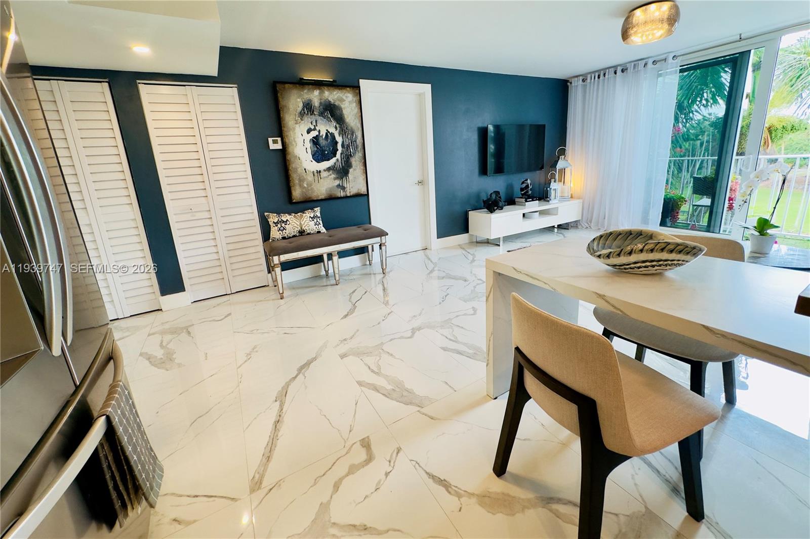 A dining and living area features white marble floors, a dark blue accent wall, and balcony — 1740 NW N River Dr # 626, Miami FL 33125, MIAMI, FL