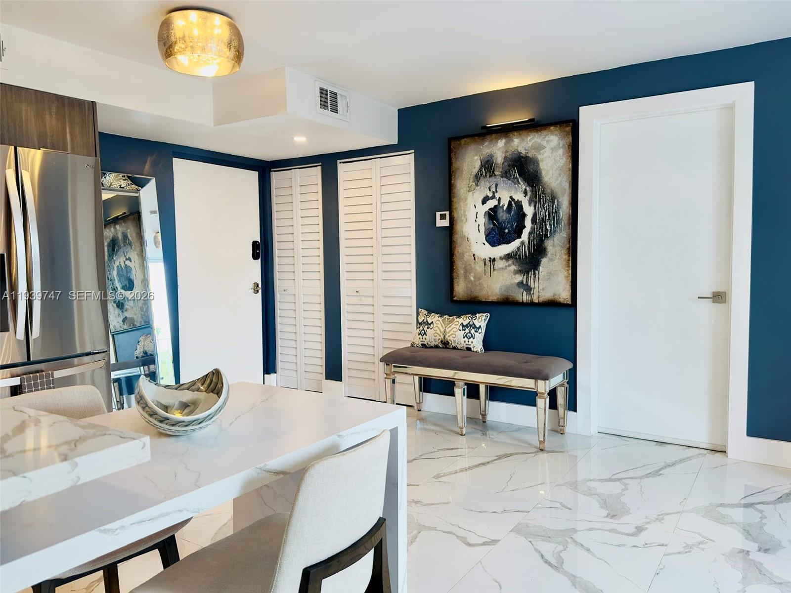 A dining area features a marble table, white tiled floors, and a dark blue accent wall — 1740 NW N River Dr # 626, Miami FL 33125, MIAMI, FL
