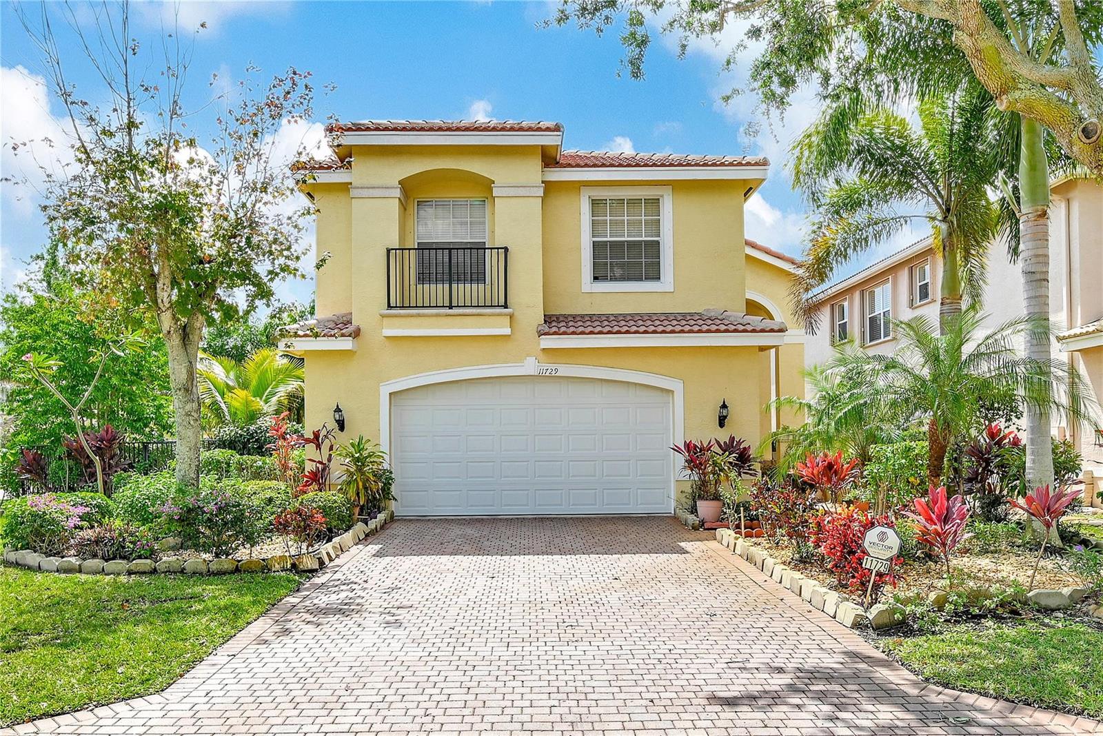 A two-story yellow house features a paved driveway, a two-car garage, and a small balcony — 11729 Rock Lake Terrace, Boynton Beach FL 33473, BOYNTON BEACH, FL