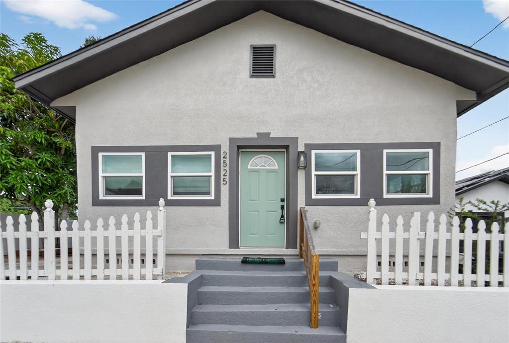 A light gray house features a mint green front door, white picket fence, and concrete steps — 2525 W BEACH STREET, TAMPA, FL