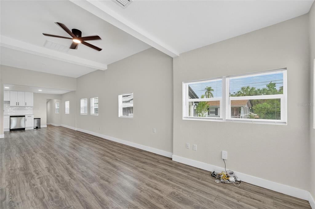 A bright living area features wood-look flooring, a ceiling fan, and multiple windows — 2525 W BEACH STREET, TAMPA, FL