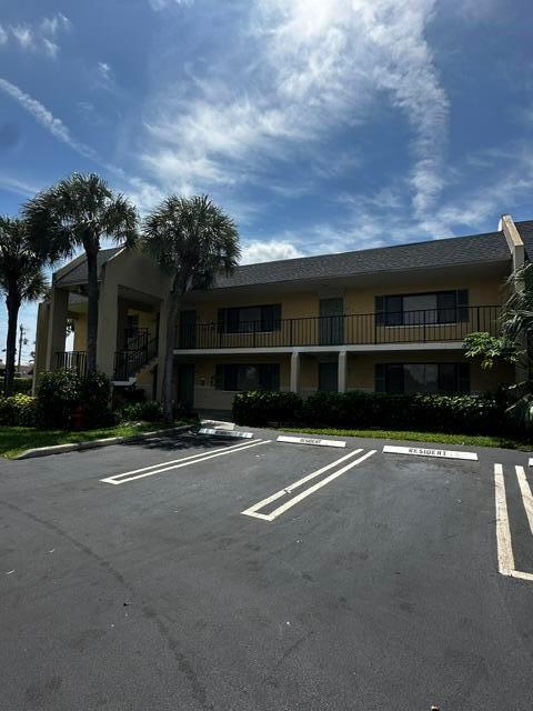 A two-story apartment building features a tan exterior, dark roof, and palm trees — 704 Meadows Circle # 704, Boynton Beach FL 33436, BOYNTON BEACH, FL
