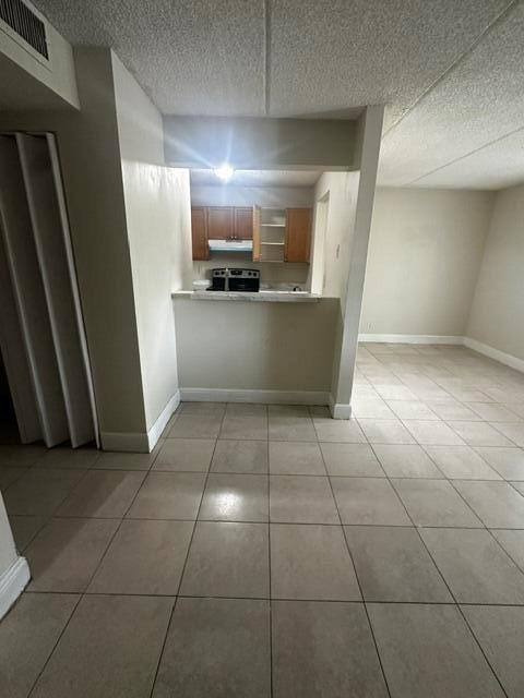 A kitchen with wooden cabinets and a pass-through window overlooks a tiled living area — 704 Meadows Circle # 704, Boynton Beach FL 33436, BOYNTON BEACH, FL