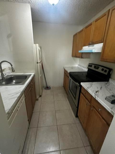 A galley kitchen features wood cabinets, white countertops, a stainless steel stove, and tile flooring — 704 Meadows Circle # 704, Boynton Beach FL 33436, BOYNTON BEACH, FL