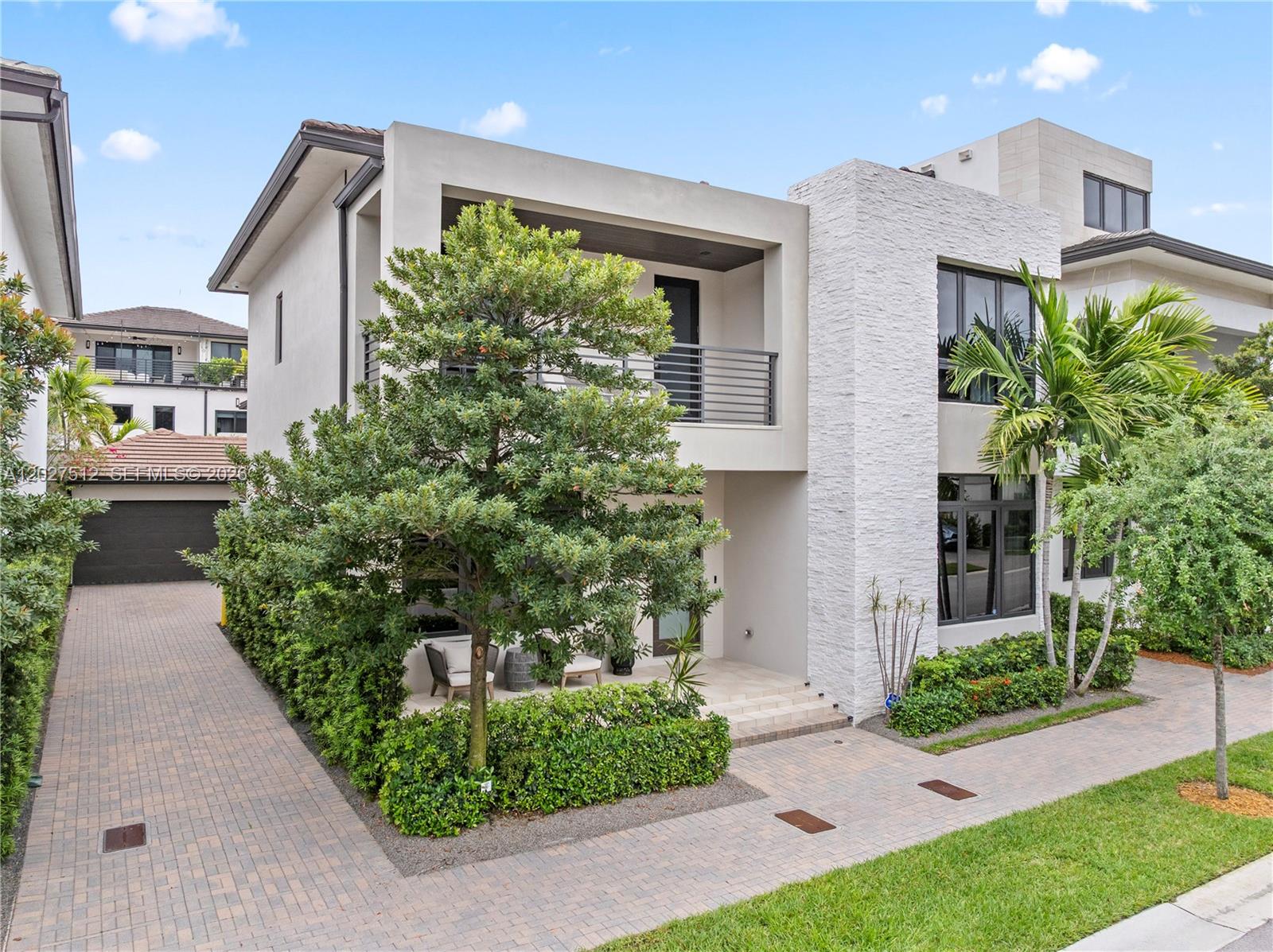 A modern two-story house features a stone facade, a balcony, and a paved driveway — 8162 NW 48th Ter, Doral FL 33166, DORAL, FL