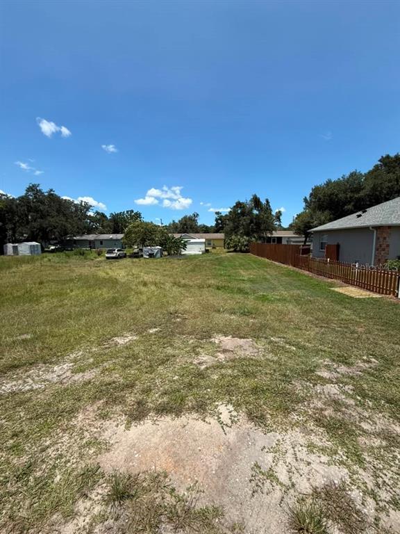 A grassy, vacant residential lot features a wooden fence along the right side — 27283 THRUSH AVENUE, BROOKSVILLE, FL