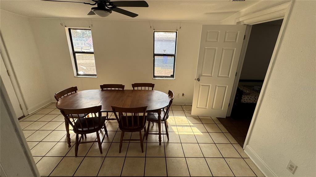 A dining room with a wooden table, six chairs, tiled floors, and two windows — 2925 BELLWOOD AVENUE, LAKELAND, FL