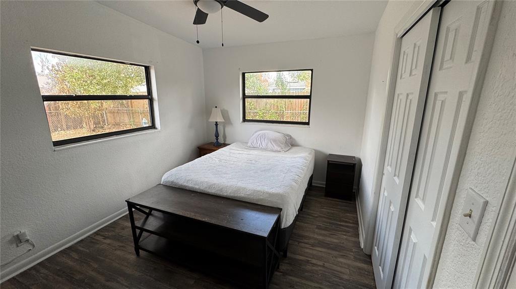 A bedroom features a bed, a dark wood bench, two windows, and white closet doors — 2925 BELLWOOD AVENUE, LAKELAND, FL