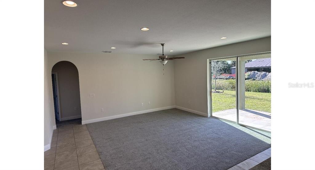 A living room features gray carpeting, recessed lighting, a ceiling fan, and sliding glass doors — 2573 TULSA AVENUE, NORTH PORT, FL