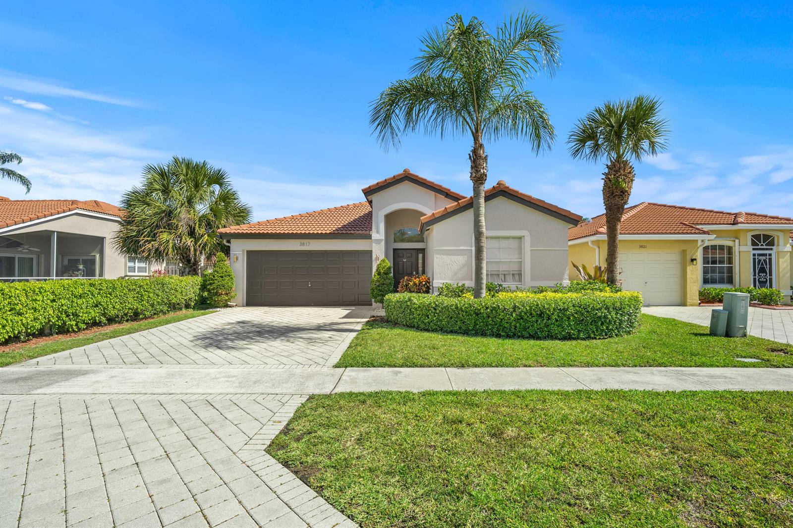 A single-story suburban house features a tiled roof, a paved driveway, and palm trees — 3817 Miramontes Circle, Wellington FL 33414, WELLINGTON, FL