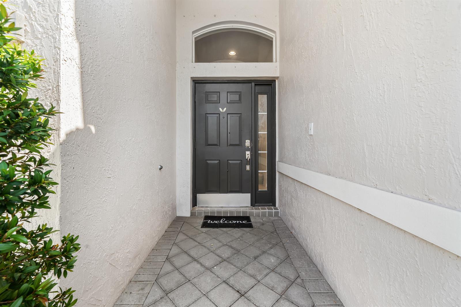 A dark front door with a side window sits at the end of a tiled entryway — 3817 Miramontes Circle, Wellington FL 33414, WELLINGTON, FL