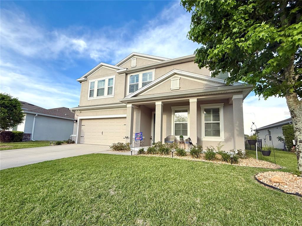 A two-story suburban house with a beige stucco exterior, a garage, and a front porch — 5655 SW 50TH AVENUE, OCALA, FL