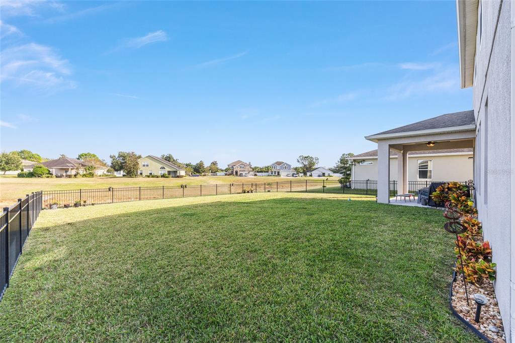 A fenced backyard features a grassy lawn and a covered patio attached to a house — 5655 SW 50TH AVENUE, OCALA, FL