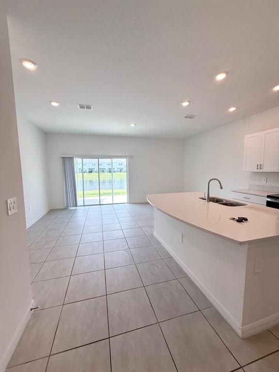 A kitchen with a large island and tile flooring overlooks a living area with sliding doors — 3519 MAYFAIR STREET, KISSIMMEE, FL