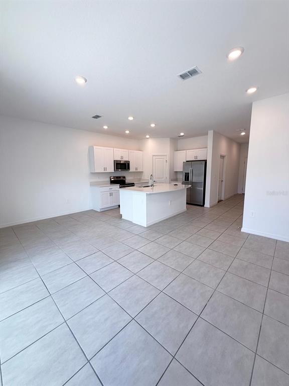 A kitchen with white cabinets, a center island, and tile flooring in an open floor plan — 3519 MAYFAIR STREET, KISSIMMEE, FL
