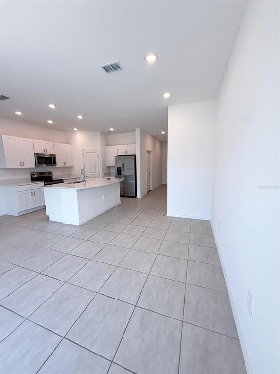 A kitchen with white cabinets, stainless steel appliances, and a central island with tile flooring — 3519 MAYFAIR STREET, KISSIMMEE, FL