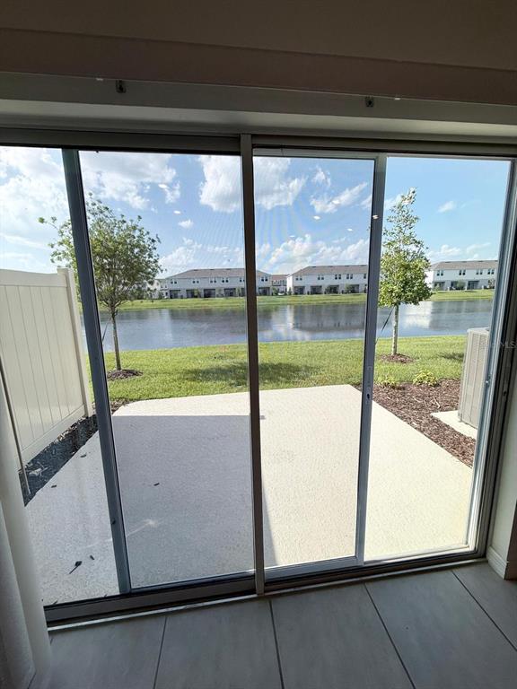 A view of a patio and lake through a sliding glass door — 3519 MAYFAIR STREET, KISSIMMEE, FL