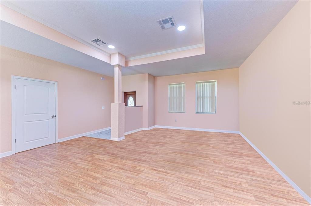 An empty room with light wood-look flooring, peach walls, and a recessed tray ceiling — 397 DONIPHAN DRIVE, PORT CHARLOTTE, FL