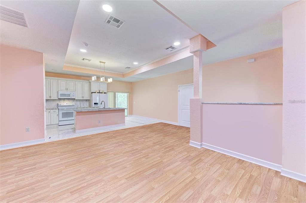 An open-concept kitchen and living area featuring light wood flooring and peach-colored walls — 397 DONIPHAN DRIVE, PORT CHARLOTTE, FL