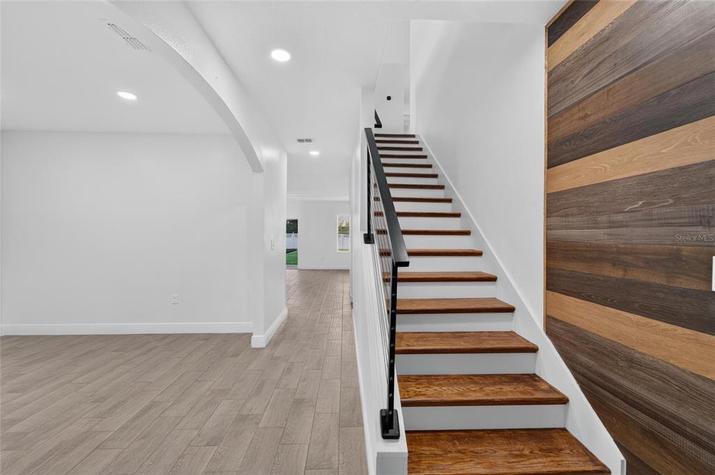 A staircase with wood treads and a metal railing stands beside a wood-paneled wall — 9637 TRONCAIS CIRCLE, THONOTOSASSA, FL