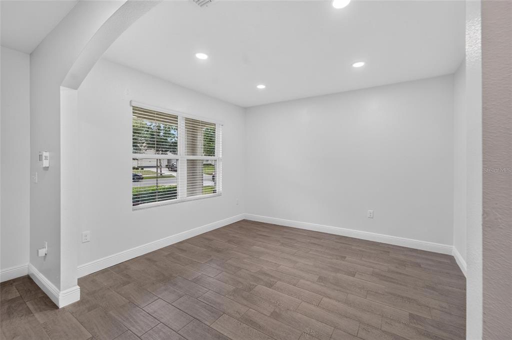An empty room features light gray walls, recessed lighting, and dark wood-look tile flooring — 9637 TRONCAIS CIRCLE, THONOTOSASSA, FL