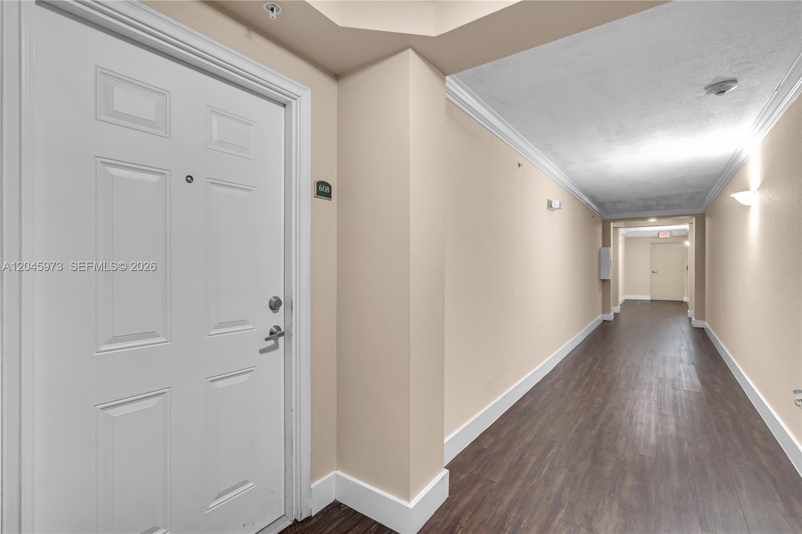 A hallway with wood-look flooring leads to a white door labeled 608 — 1690 SW 27th Ave # 608, Miami FL 33145, MIAMI, FL