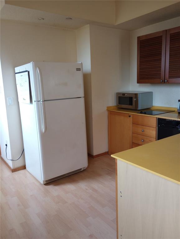 A kitchen features a white refrigerator, light wood cabinets, a microwave, and a yellow countertop — 101 PALM HARBOR PARKWAY UNIT C226, PALM COAST, FL