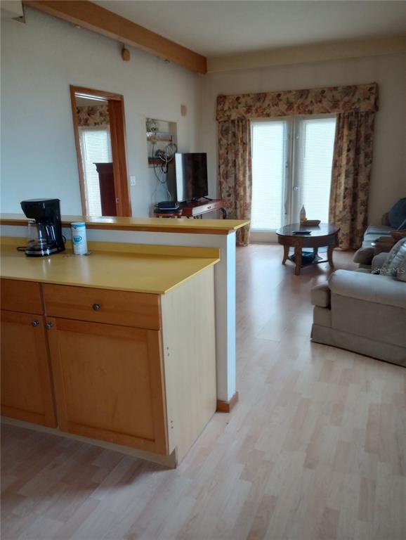 A kitchen counter with a coffee maker overlooks a living room with light wood flooring — 101 PALM HARBOR PARKWAY UNIT C226, PALM COAST, FL