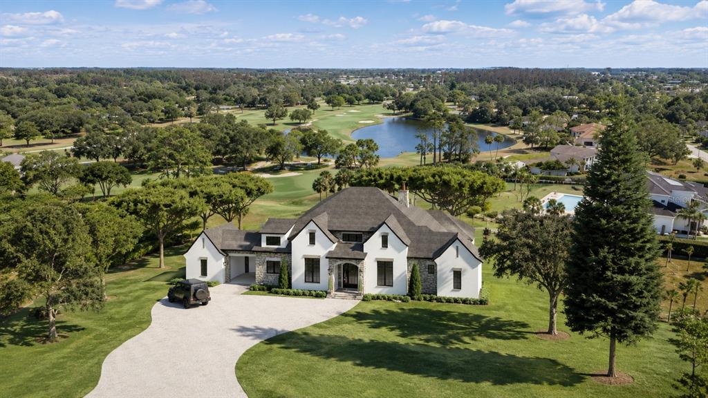 An aerial view of a white, multi-gabled house with a stone facade and circular driveway — 29244 WHIPPORWILL LANE, WESLEY CHAPEL, FL