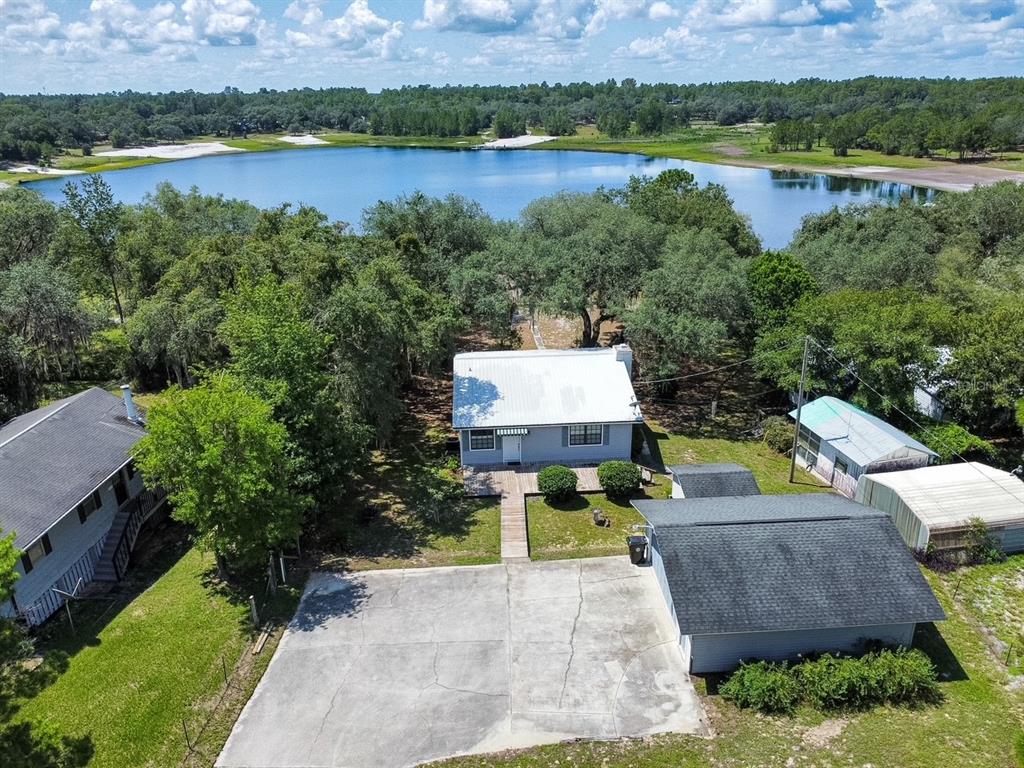 An aerial view shows a house with a metal roof, a detached garage, and a lake — 5616 SILVER SANDS CIRCLE, KEYSTONE HEIGHTS, FL