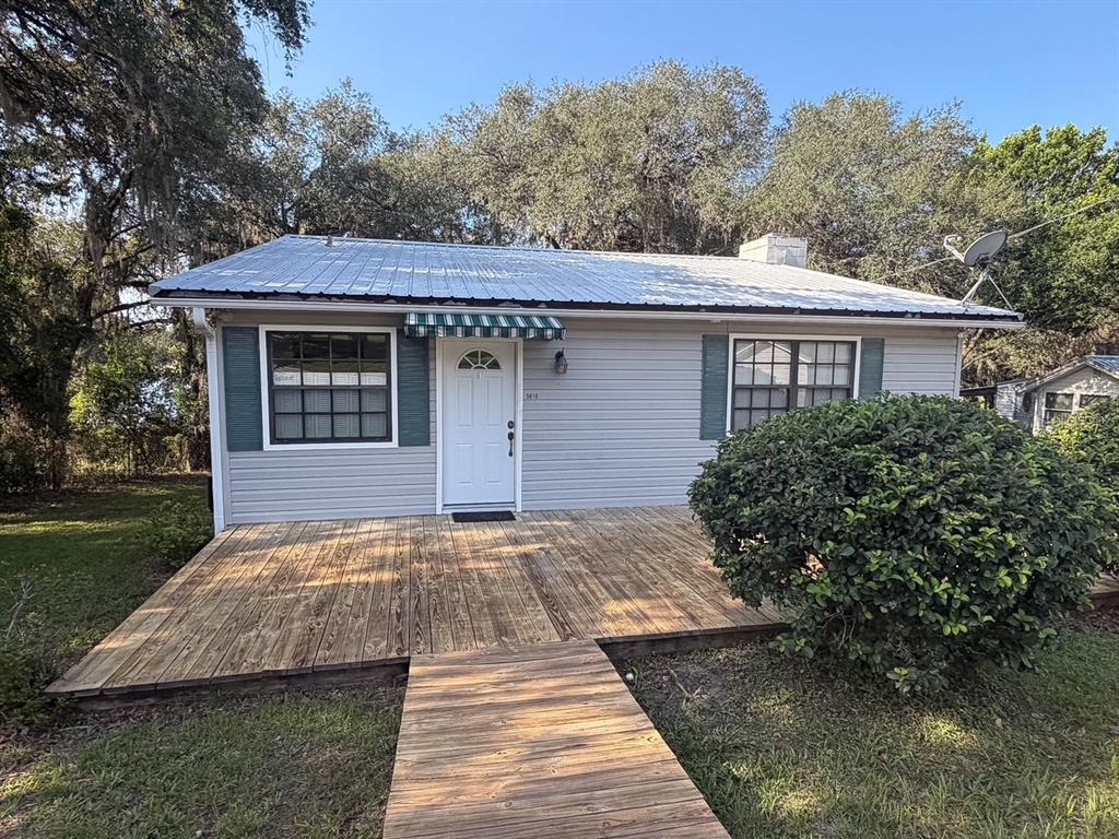 A single-story house with light gray siding, a metal roof, and a large wooden deck — 5616 SILVER SANDS CIRCLE, KEYSTONE HEIGHTS, FL