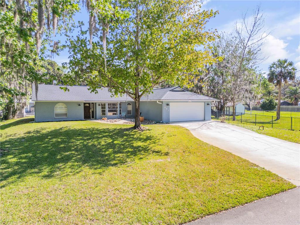 A single-story gray brick house with a two-car garage and a large front yard — 451 PALM DRIVE, NEW SMYRNA BEACH, FL