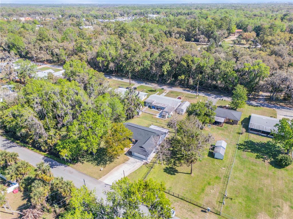 An aerial view shows a single-story house with a black roof surrounded by trees — 451 PALM DRIVE, NEW SMYRNA BEACH, FL
