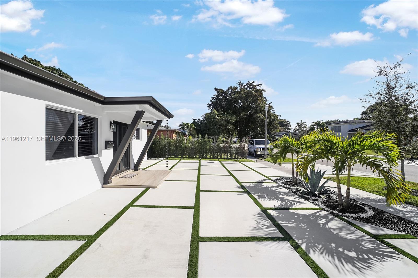 A modern house exterior features a concrete paver driveway with artificial turf strips and landscaping — 45 NE 124th Ter, North Miami FL 33161, NORTH MIAMI, FL