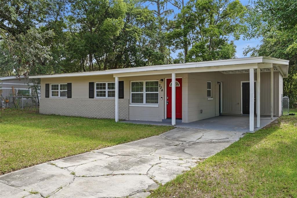 A single-story house with a beige exterior, a red front door, and an attached carport — 224 MURRY DRIVE, ORLANDO, FL
