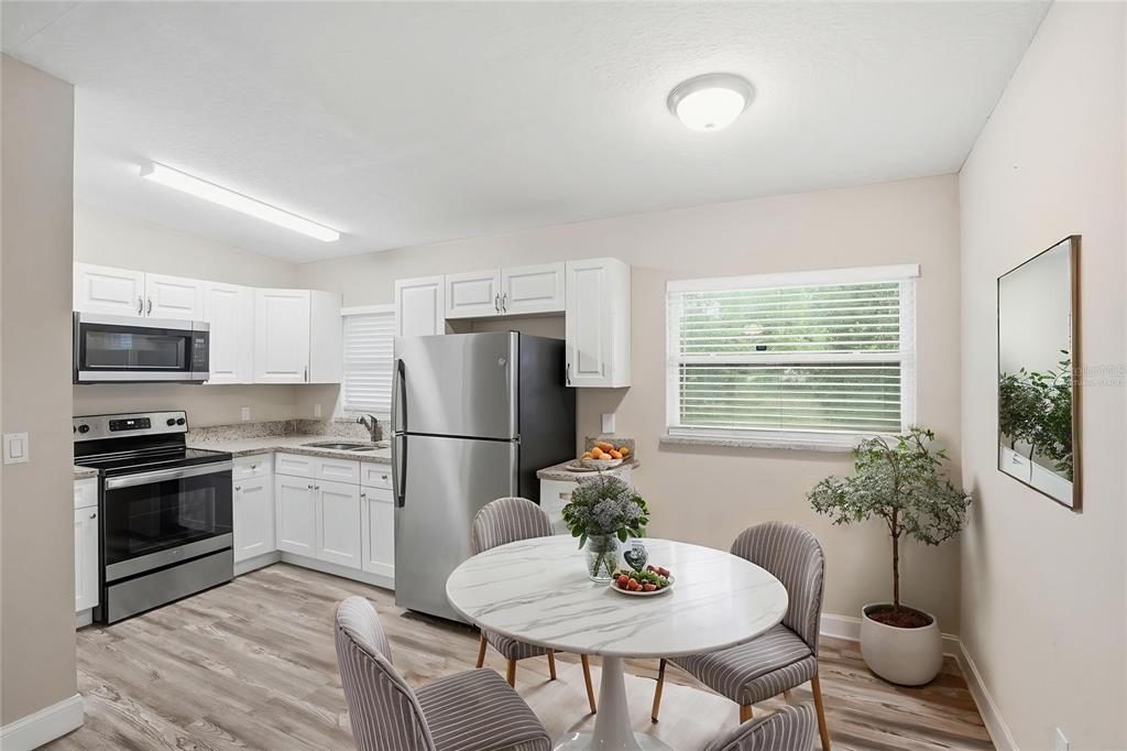 A kitchen with white cabinets, stainless steel appliances, and a round dining table with chairs — 224 MURRY DRIVE, ORLANDO, FL