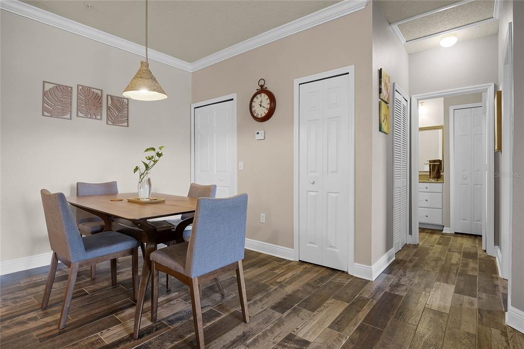 A dining area features a wooden table, four gray chairs, and wood-look flooring — 430 SOUTHERN PECAN CIRCLE UNIT 207, WINTER GARDEN, FL