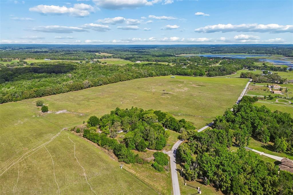 An aerial view shows a large, open grassy field bordered by trees and a road — BAYHEAD ROAD Lot 8, DADE CITY, FL