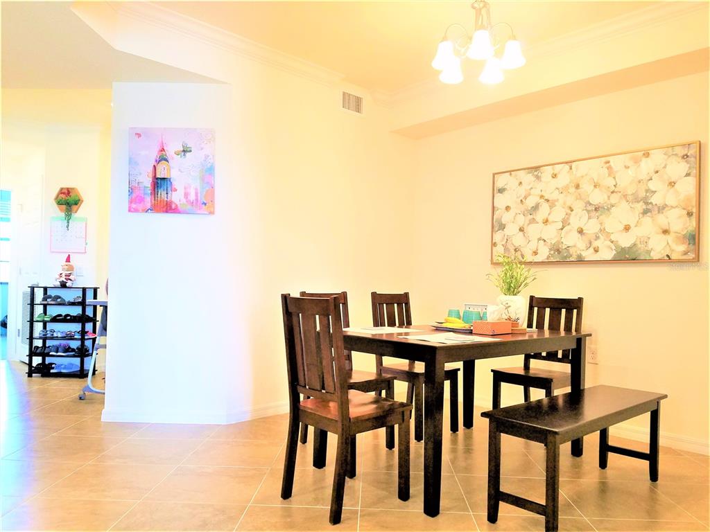 A dining area features a dark wood table with chairs and a bench on tile flooring — 17108 VARDON TERRACE UNIT 208, LAKEWOOD RANCH, FL