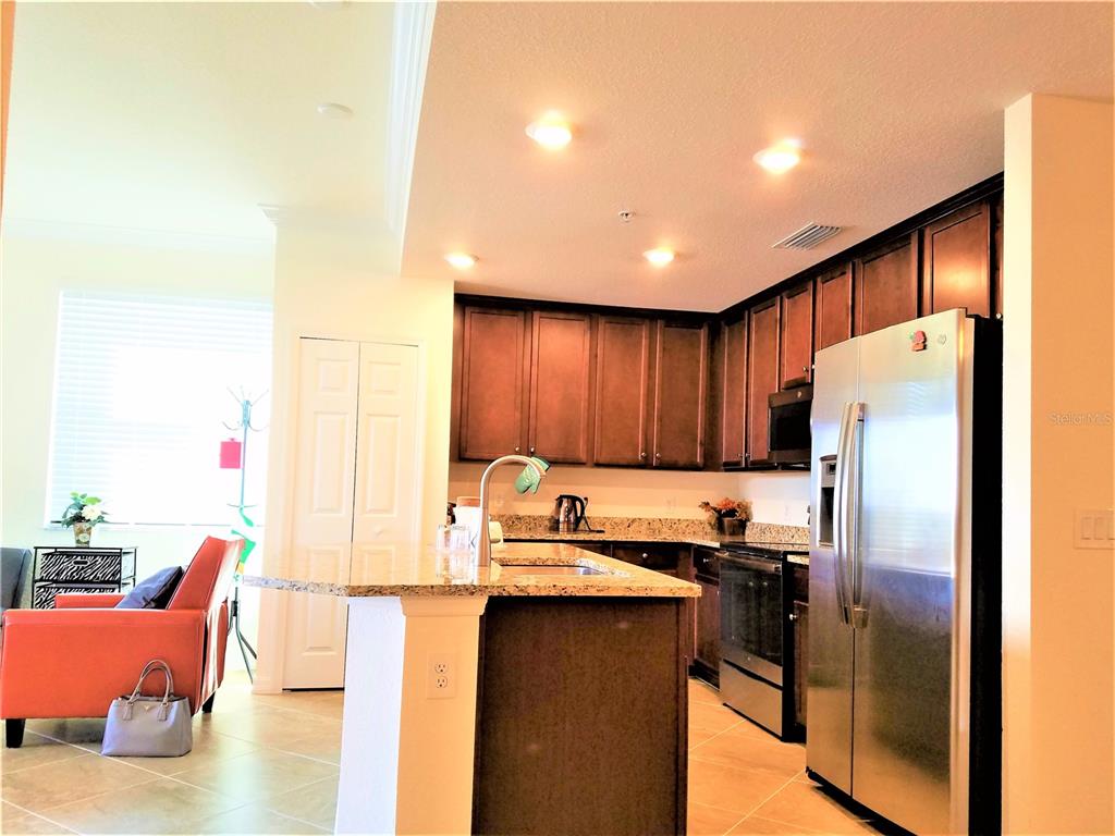 A kitchen with dark wood cabinets, granite countertops, and stainless steel appliances — 17108 VARDON TERRACE UNIT 208, LAKEWOOD RANCH, FL