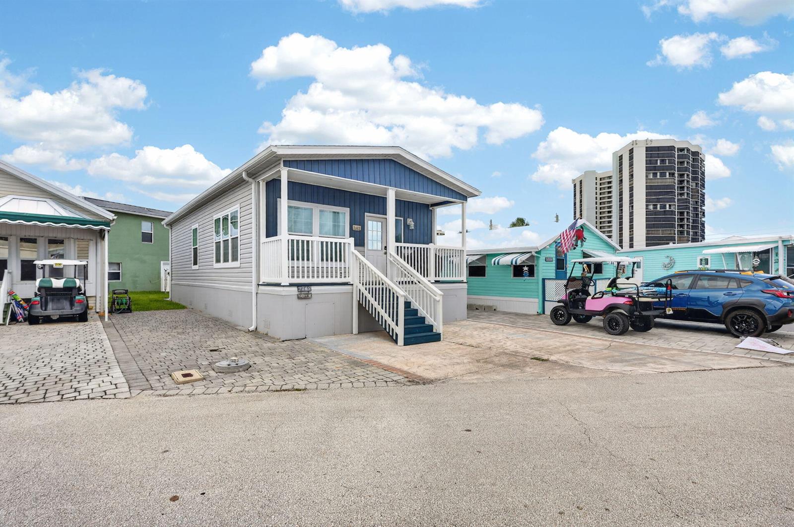 A blue and white manufactured home with a front porch sits on a paved lot — 2149 Nettles Boulevard, Jensen Beach FL 34957, JENSEN BEACH, FL