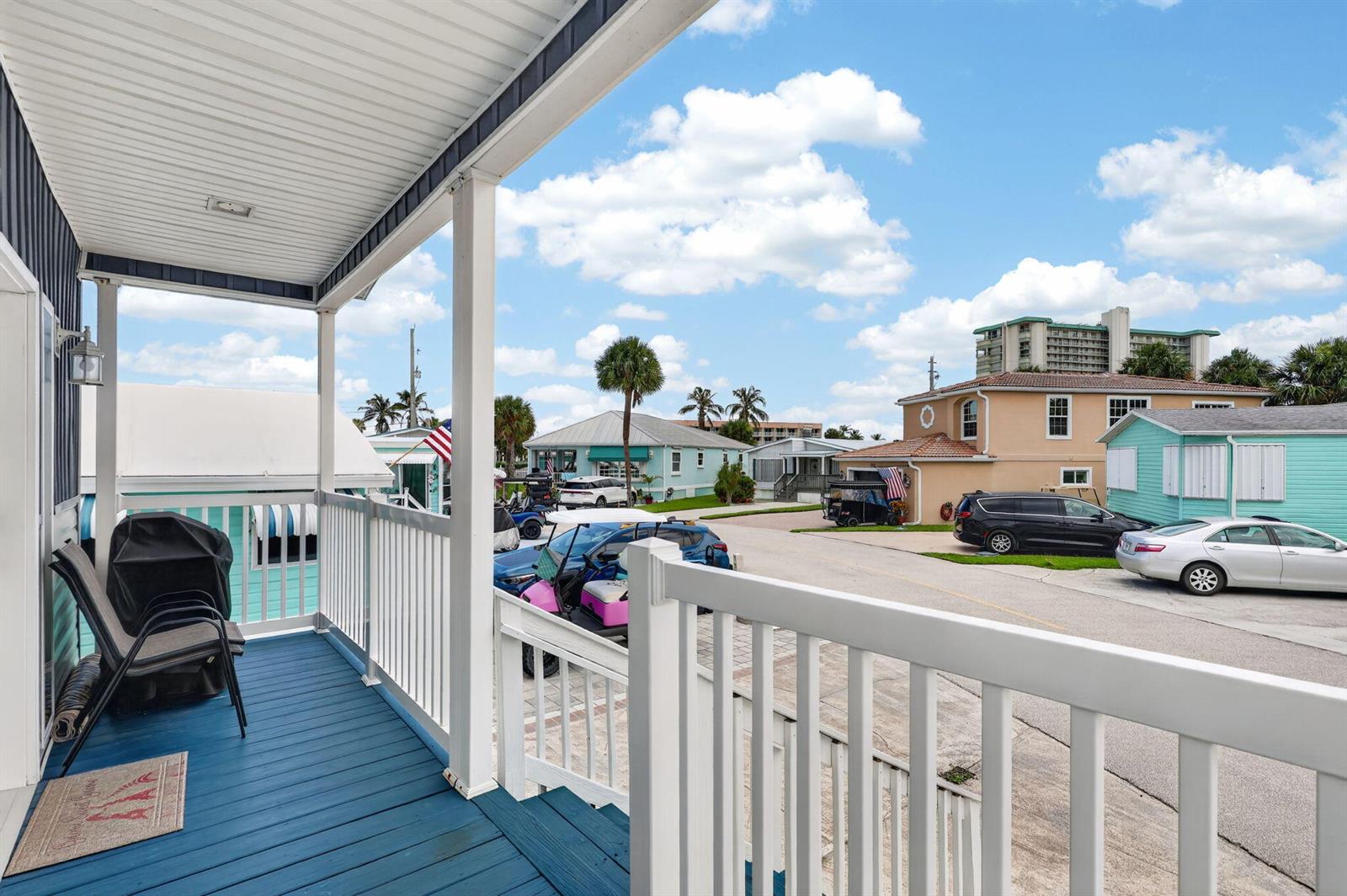 A blue-painted porch with white railings overlooks a neighborhood street with houses and cars — 2149 Nettles Boulevard, Jensen Beach FL 34957, JENSEN BEACH, FL