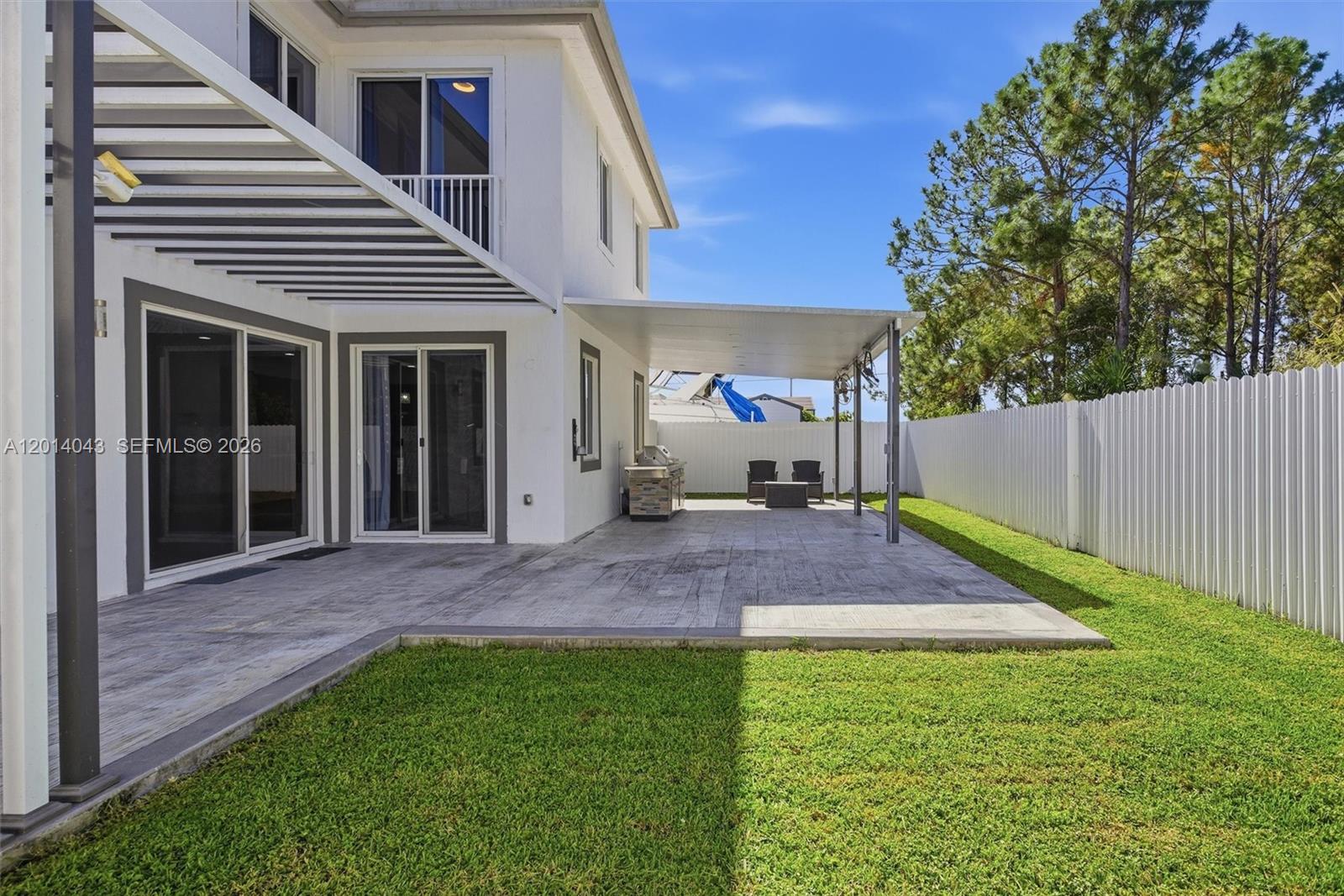A white two-story house features a covered patio, outdoor grill, and a fenced backyard — 18350 SW 139th Path, Miami FL 33177, MIAMI, FL