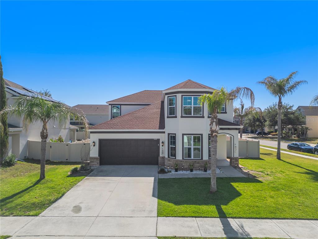 A two-story suburban house with a dark garage, stone accents, and a palm tree — 2001 RED BLUFF AVENUE, APOPKA, FL