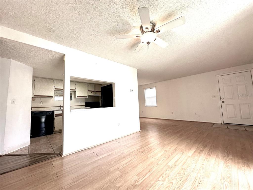 A living room with light wood flooring and a pass-through window to the kitchen — 135 HUNTER LAKE DRIVE UNIT F, OLDSMAR, FL