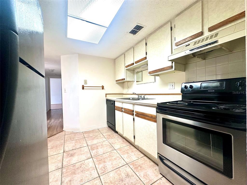 A kitchen features white cabinets, stainless steel appliances, and light-colored tile flooring — 135 HUNTER LAKE DRIVE UNIT F, OLDSMAR, FL
