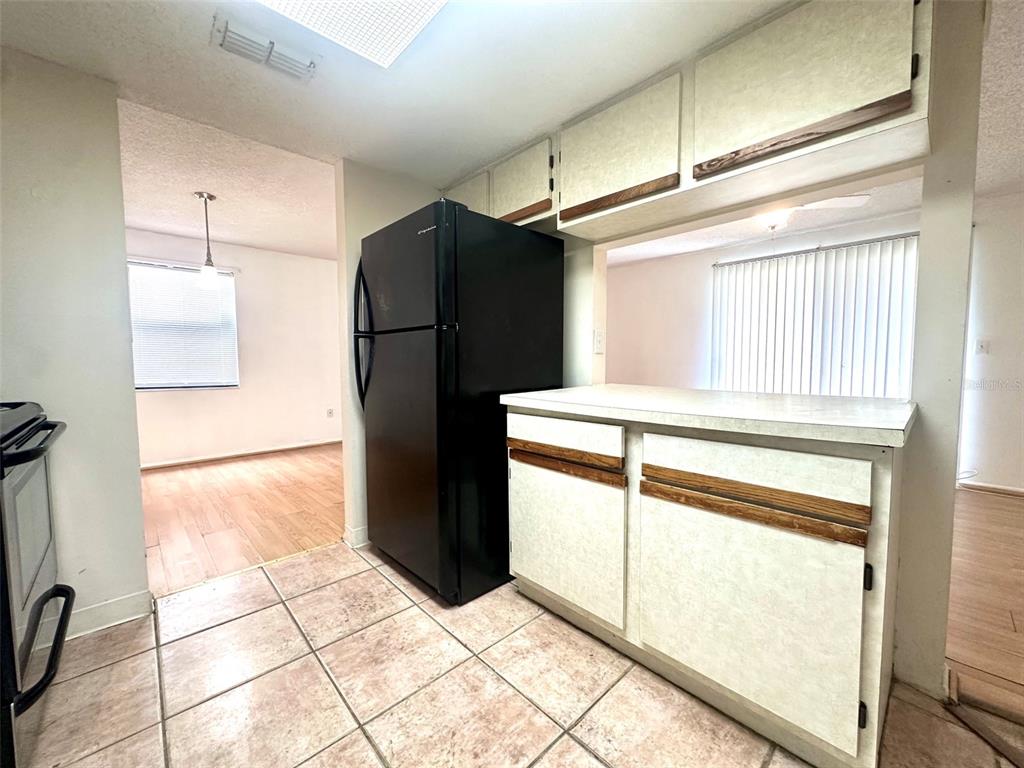 A kitchen with tile flooring, a black refrigerator, and white cabinetry with wood trim — 135 HUNTER LAKE DRIVE UNIT F, OLDSMAR, FL